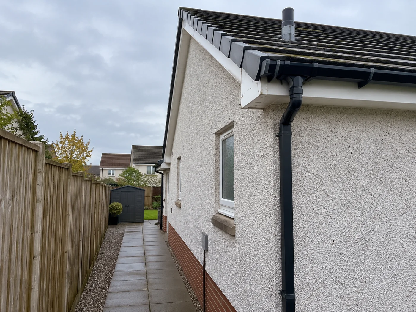 Paved side path beside a house with roof eaves above